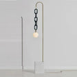 A brass rod hooking over to hang a dark glass chain and a white globe above a stone base