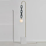 A brass rod hooking over to hang a dark glass chain and a white globe above a stone base