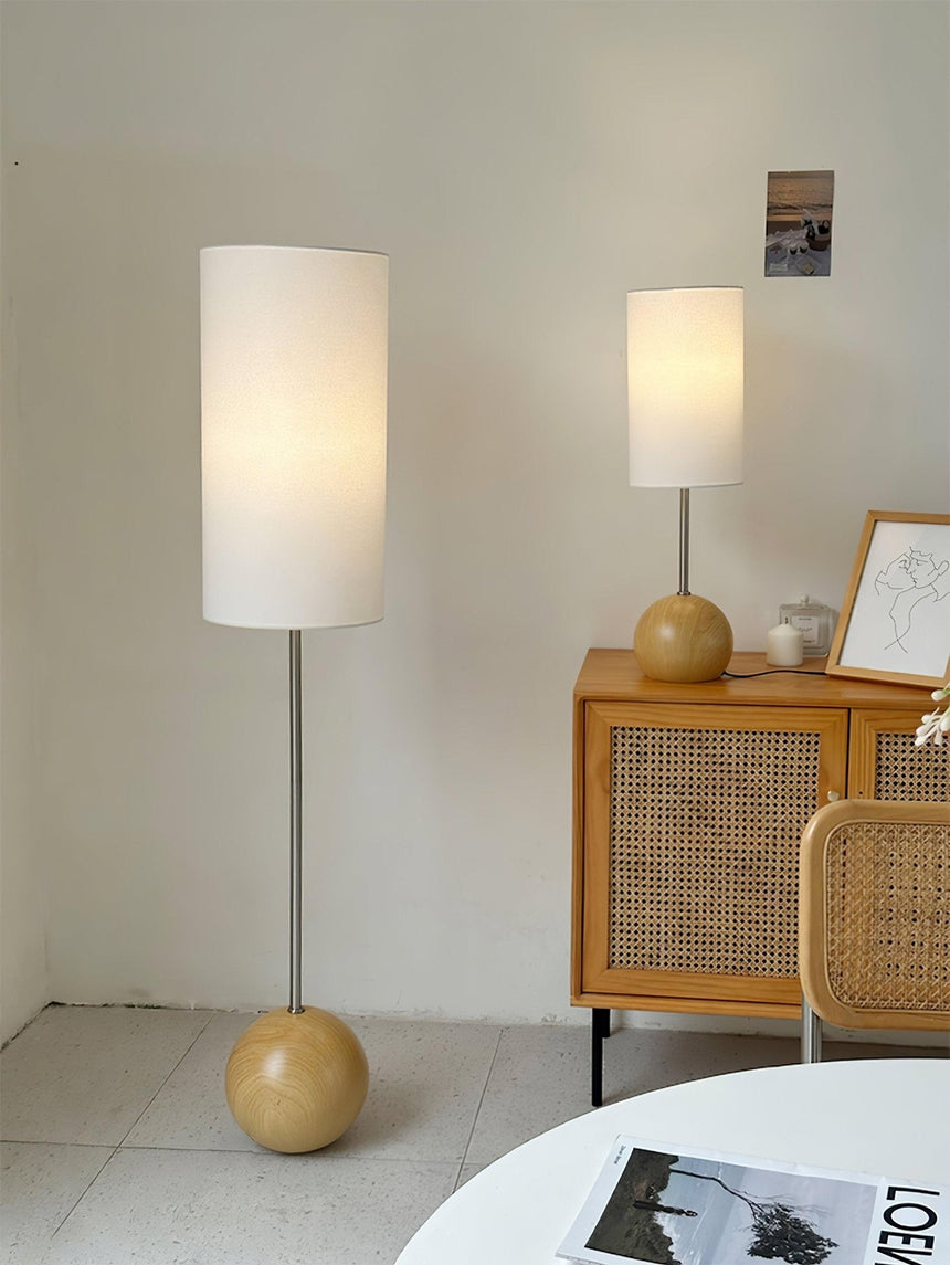 Natural wood globe table lamp in a pale room beside a rattan sideboard
