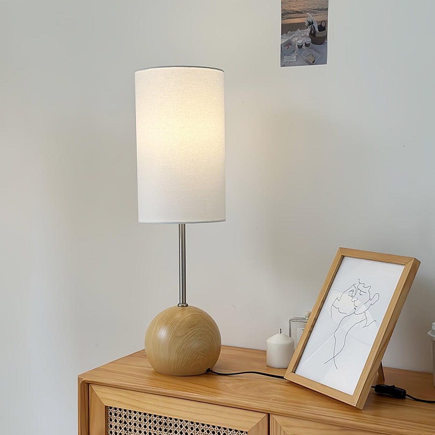 Natural wood globe table lamp on a cane fronted sideboard beside a frame