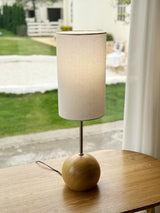 Natural wood globe table lamp on a table in front of a garden window