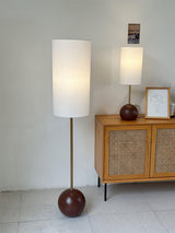 Walnut globe table lamp seen full length in a room beside a sideboard