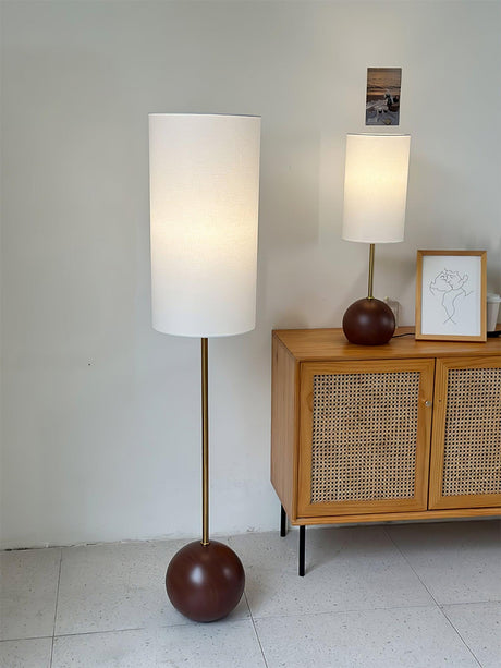 Walnut globe table lamp beside a sideboard in a pale tiled room