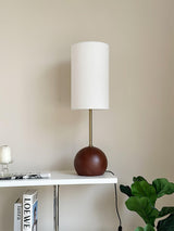 Walnut globe table lamp lit on a console beside books and a candle