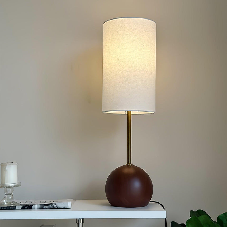 Globe table lamp with the walnut sphere lit on a white console