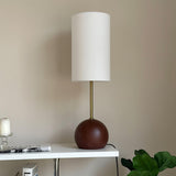Close view of the walnut sphere base under the slim stem and shade