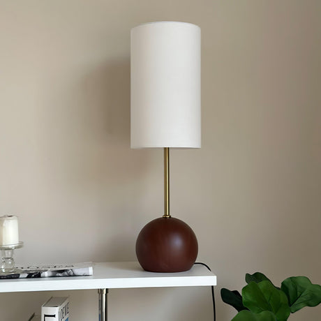 Close view of the walnut sphere base under the slim stem and shade