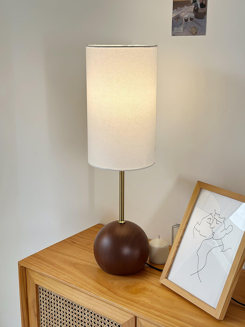 Walnut globe table lamp on a cane fronted sideboard beside a framed drawing