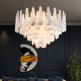 The lit chandelier in a deep blue room with artwork, a plant and chairs