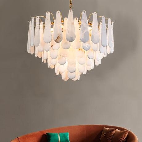 The lit chandelier on a warm gray wall above a deep orange sofa