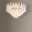 A tiered chandelier of white alabaster petals on a gold frame, lit