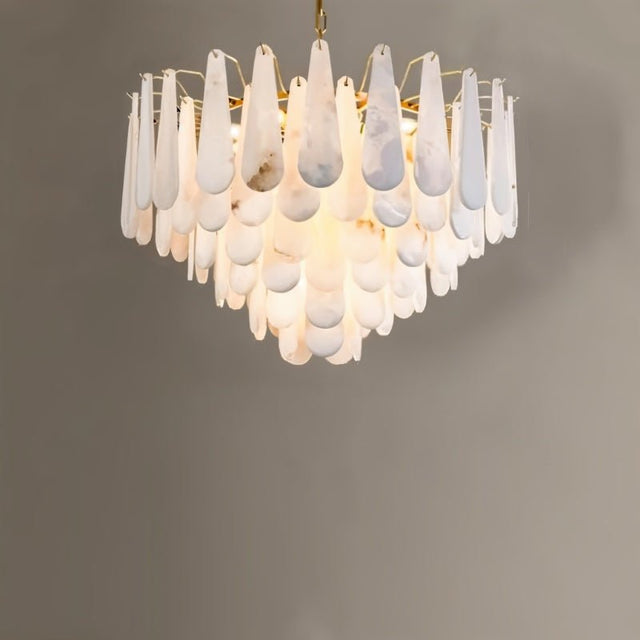 A tiered chandelier of white alabaster petals on a gold frame, lit