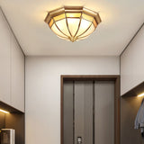 Faceted brass dome ceiling light on a white ceiling by a doorway