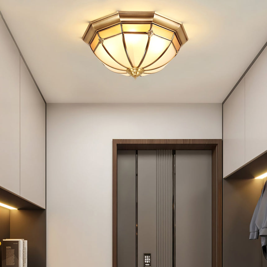 Faceted brass dome ceiling light on a white ceiling by a doorway