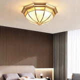 Faceted brass dome ceiling light above a bed with a dark wall