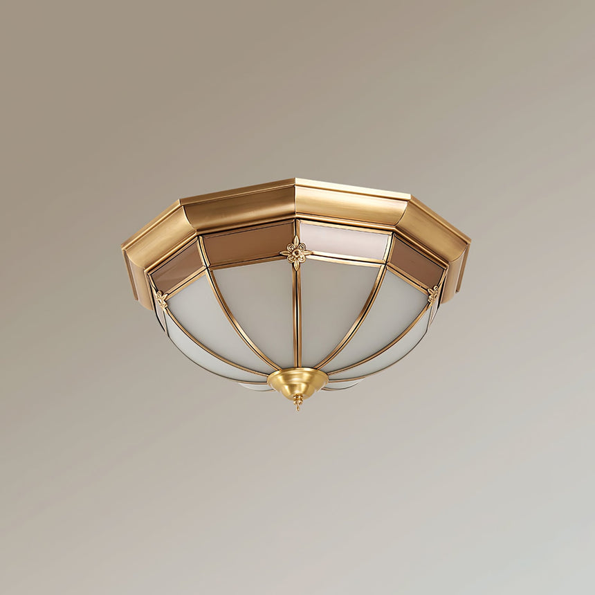 Faceted brass dome ceiling light seen at an angle on a pale backdrop
