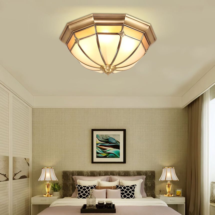 Faceted brass dome ceiling light above a bed with two table lamps