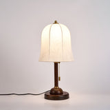 Gold and white table lamp lit from the front, the bell shade glowing