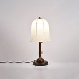 Gold and white table lamp lit against a soft neutral ground