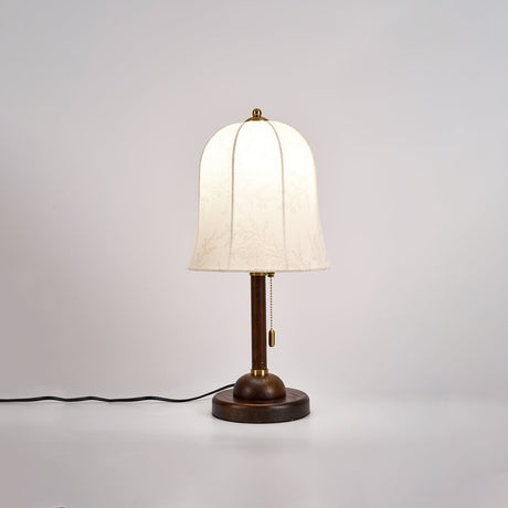 Gold and white table lamp lit against a soft neutral ground