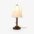 Gold and white table lamp with a bell shade on a walnut stem