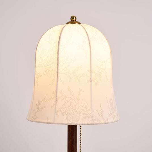 Close view of the lit bell shade and the pull chain under it