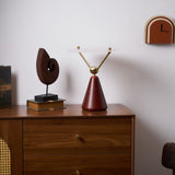 Gold and white table lamp on a dresser beside a cane backed chair