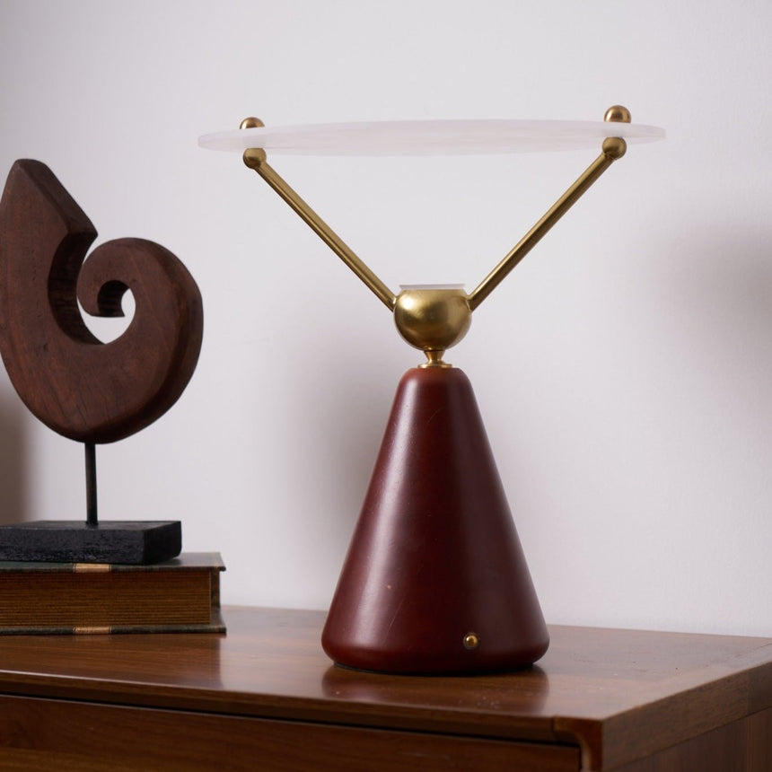 Gold and white table lamp lit and seen at an angle on a chest