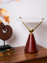 Gold and white table lamp lit on a chest beside a spiral sculpture