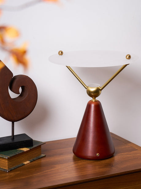 Gold and white table lamp lit on a chest beside a spiral sculpture