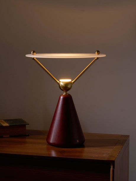 Gold and white table lamp lit on a wooden chest against a pale wall