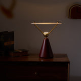 Gold and white table lamp lit on a wooden chest in a dim room