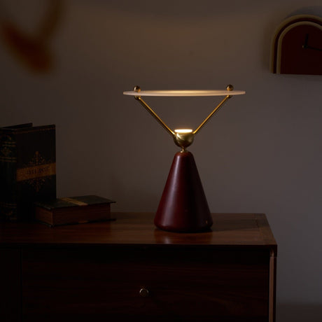 Gold and white table lamp lit on a wooden chest in a dim room