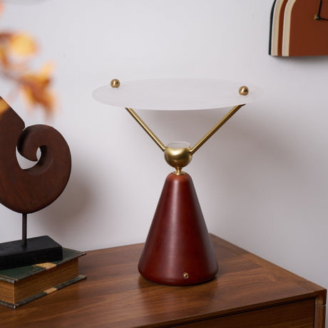 Gold and white table lamp lit on a walnut chest beside a sculpture