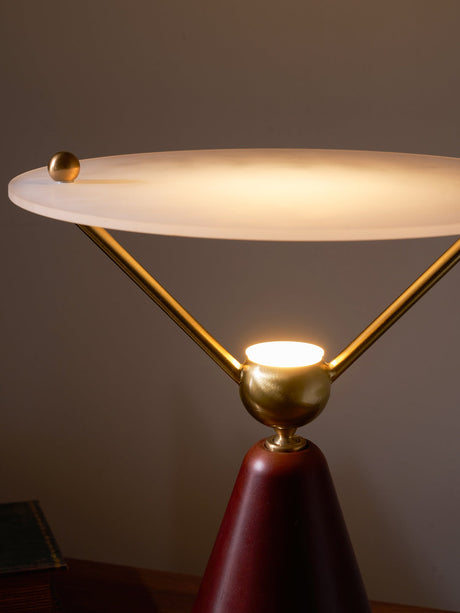 The lit underside of the frosted disc above the brass sphere