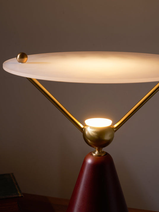 The lit underside of the frosted disc above the brass sphere