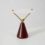 Gold and white table lamp seen at an angle against a plain ground