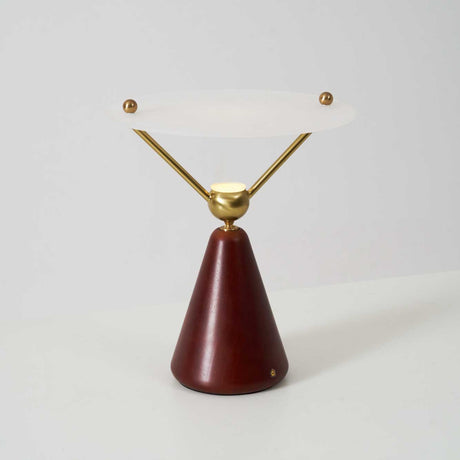 Gold and white table lamp seen at an angle against a plain ground