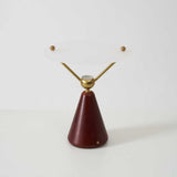 Gold and white table lamp seen from the front against a plain ground