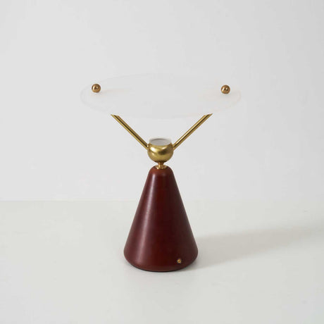 Gold and white table lamp seen from the front against a plain ground