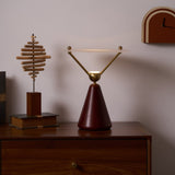 Gold and white table lamp lit beside a small brass ornament
