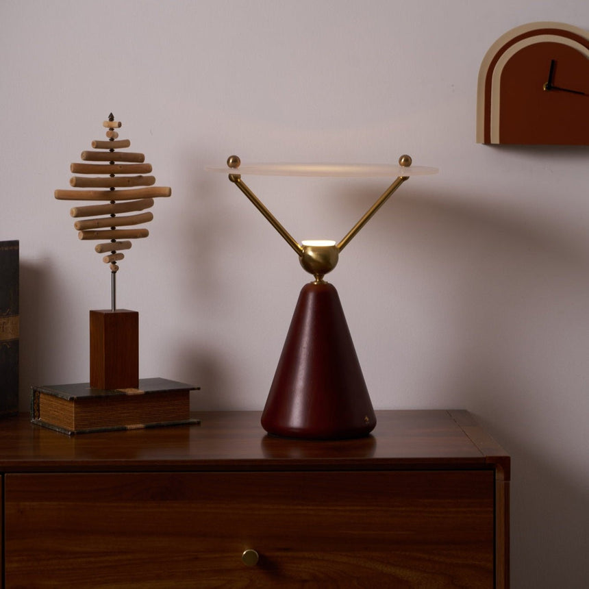 Gold and white table lamp lit beside a small brass ornament