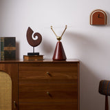 Gold and white table lamp lit on a dresser beside a carved sculpture