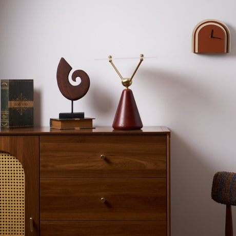 Gold and white table lamp lit on a dresser beside a carved sculpture
