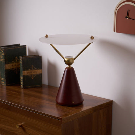 Gold and white table lamp on a dresser beside old bound books