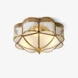 Gold and white ceiling light with a scalloped brass cage over frosted glass