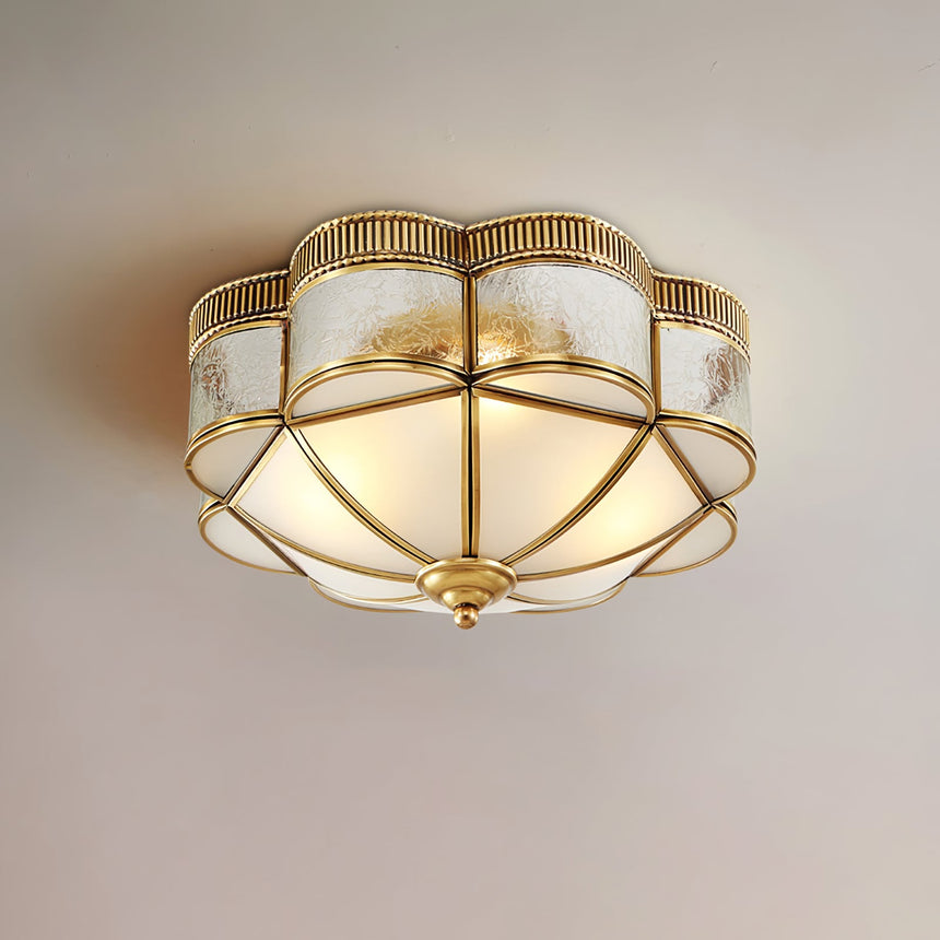 Scalloped brass ceiling light lit and seen at an angle