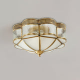Scalloped brass ceiling light seen from below with the glass lit