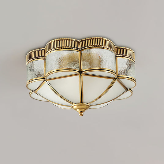 Scalloped brass ceiling light seen from below with the glass lit