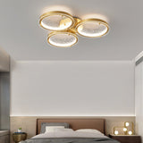 Three ring gold ceiling light above a bed with a low headboard